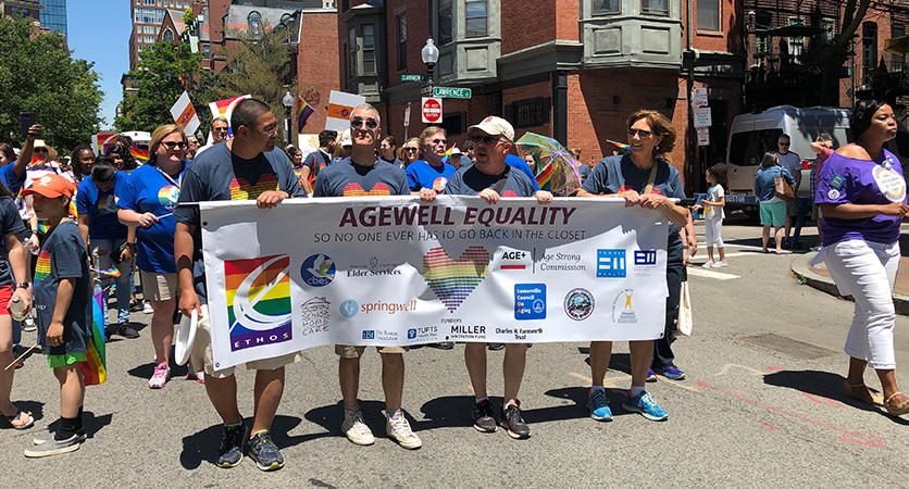 People at a pride parade, holding a banner