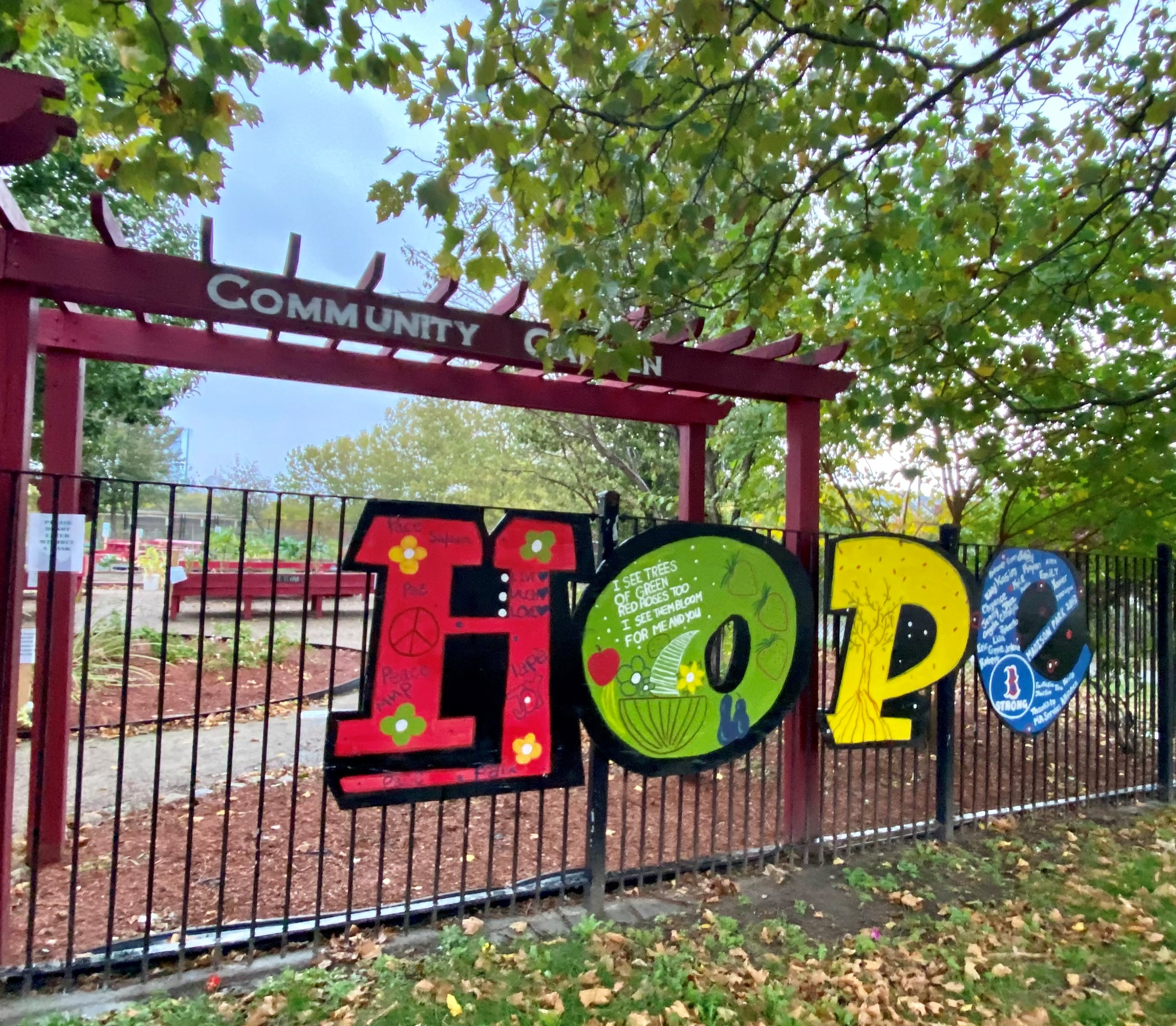 Metal fence outside garden with a colorful block letter sign spelling out hope