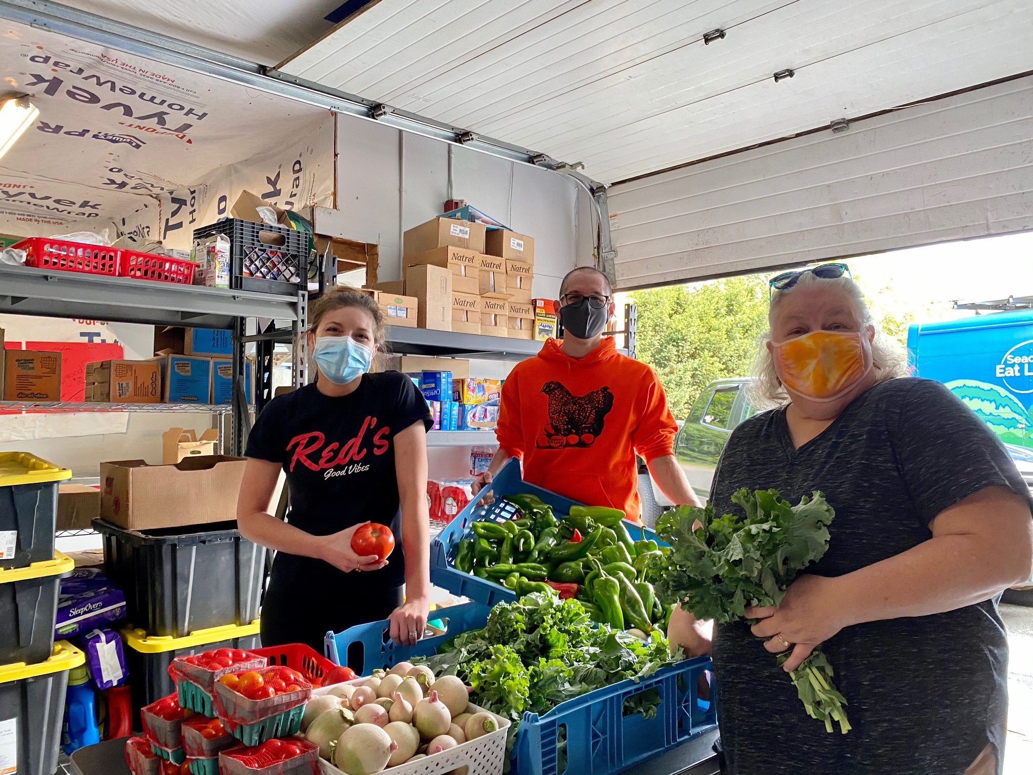 Three people posing for picture with fresh vegetables